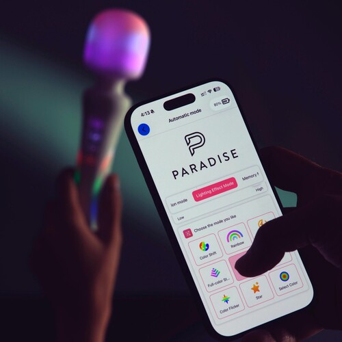 Illumination Wand Massager in hand with phone displaying the app