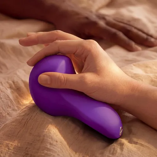 h Couples Grinding Vibrator in a hand on a bed